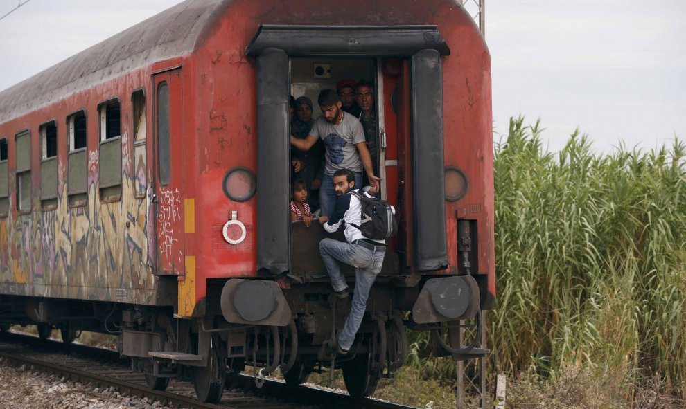 Inmigrantes se suben a un tren para dejar atrás la estación cercana a Gevgelija. REUTERS