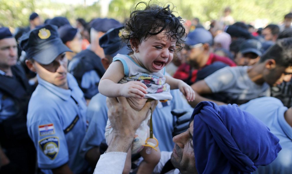 Un emigrante coge a su bebé mientras espera a subirse abordo de un bus en Tovarnik, Croacia, 17 de septiembre, 2015. REUTERS/Antonio Bronic