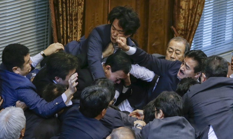 El miembro de la oposición Yukihiro Knishi (c) recibe un puñetazo del consejero del gobernante Partido Liberal Demócrata (PDL) Masahisa Sato (d) mientras se enzarzan en una pelea tras la aprobación de la polémica reforma militar en la Cámara Alta de la Di