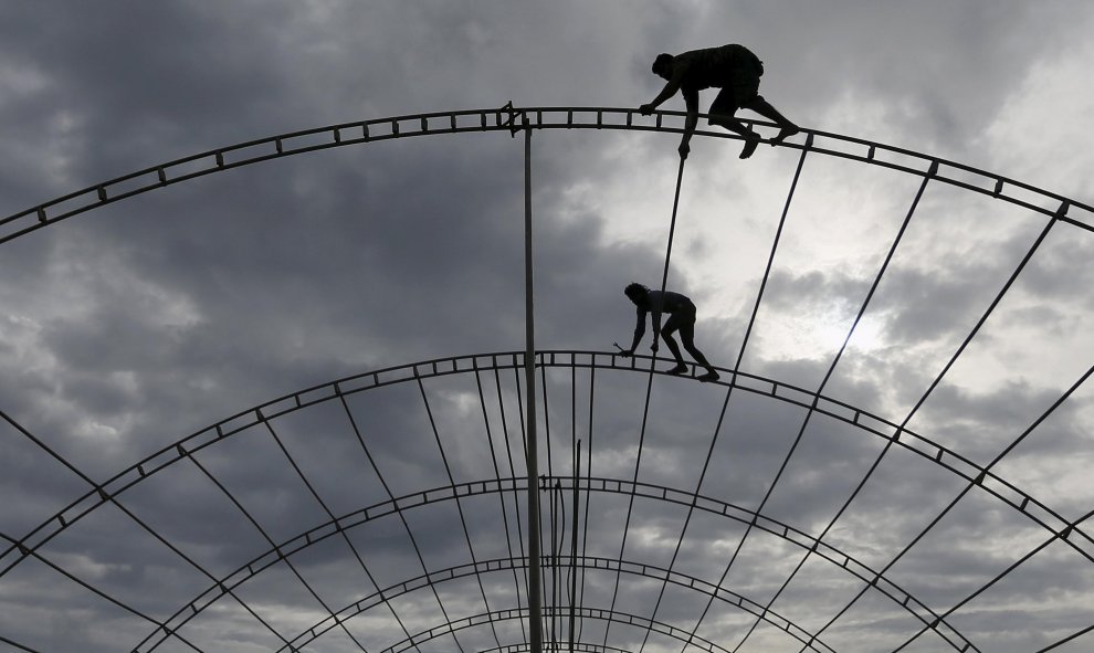 Obreros trabajan en postes de hierro durante la construcción de un escenario para un programa en Colombo. REUTERS