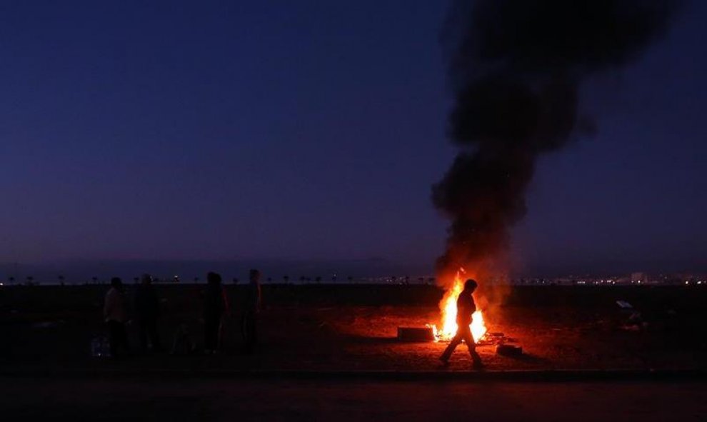 Un grupo de personas pasa la noche al aire libre entre los destrozos causados por el tsunami que arrasó Chile. EFE/Mario Ruiz