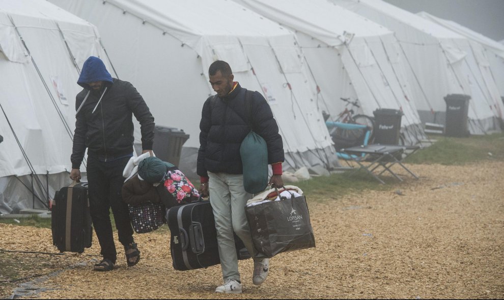 Dos refugiados trasladan sus pertenencias al abandonar un refugio temporal con temperaturas que rozan los cero grados cerca de Schwarzenborn (Alemania). EFE/Boris Roessler