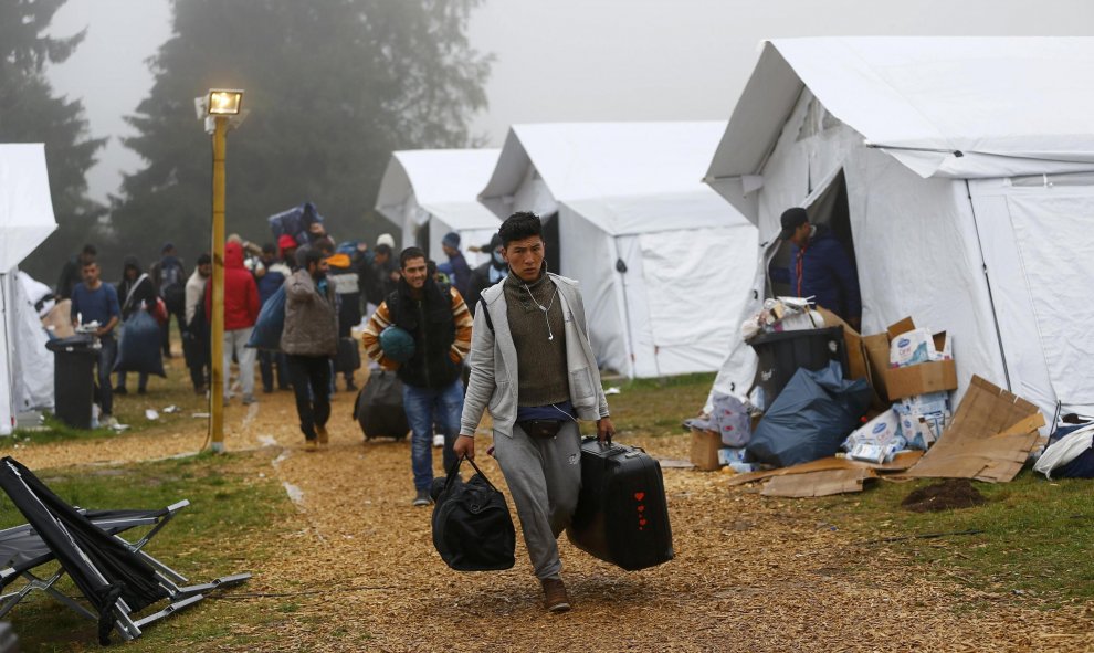 Varios refugiados con sus pertenencias se dirigen a los autobuses que los trasladarán a sus albergues de residencia definitivos, desde el refugio temporal de Schwarzenborn (Alemania). REUTERS/Kai Pfaffenbach