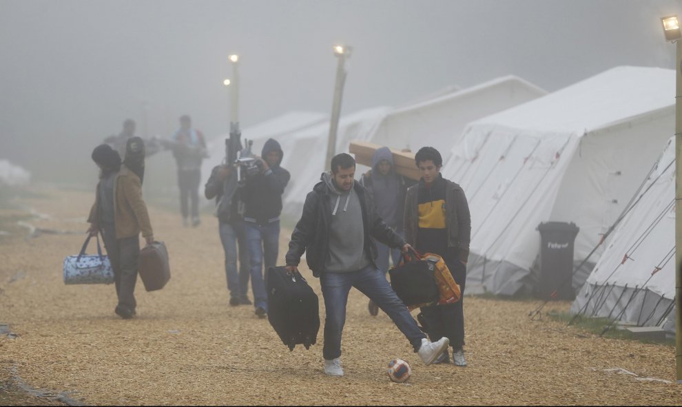 Varios refugiados con sus pertenencias se dirigen a los autobuses que los trasladarán a sus albergues de residencia definitivos, desde el refugio temporal de Schwarzenborn (Alemania). REUTERS/Kai Pfaffenbach