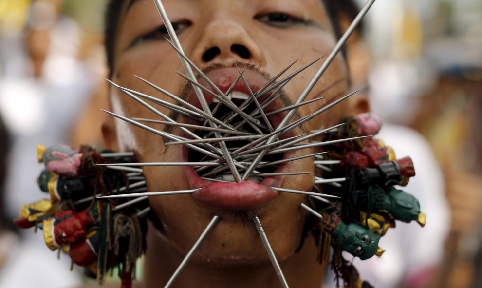 Un devoto del santuario chino Samkong  camina con agujas que le atraviesan las mejillas durante una procesión que celebra el festival anual vegetariano en Phuket, Tailandia, 16 de octubre de 2015. REUTERS / Jorge Silva