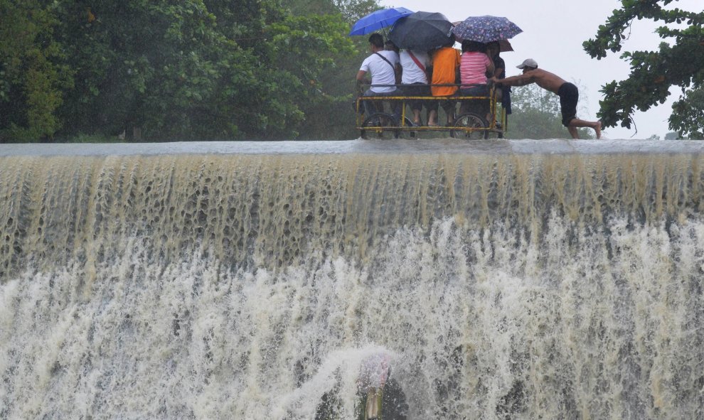 Residentes cruzan una presa, debido al aumento del agua provocado por el tifón Koppu, en la ciudad de Las Pinas, Manila. REUTERS/Esdras Acayan