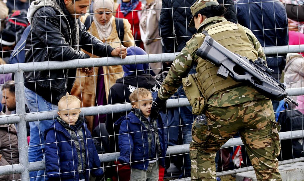 Miembros del ejército esloveno hablan con refugiados en la frontera con Austria. REUTERS / Leonhard Foeger