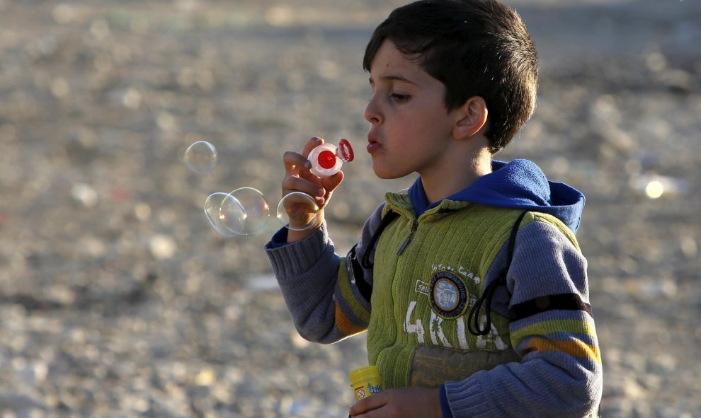 Un niño inmigrante hace pompas de jabón mientras espera a su traslado a un campo de tránsito en Gevgelija, Macedonia, después de entrar en el país por el cruce de la frontera con Grecia, 4 de noviembre de 2015. REUTERS / Ognen Teofilvovski