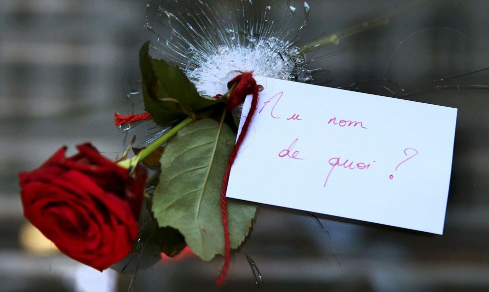 Una rosa colocada en un agujero de bala en una ventana del restaurante atacado, el día después de los atentados en París. "En nombre de qué?" , dice la nota.- REUTERS / Pascal Rossignol