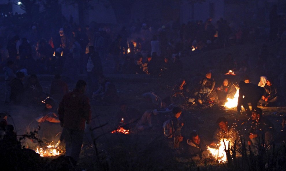 Refugiados junto a las hogueras mientras esperan para entrar en un campo de registro después de cruzar la frontera de Grecia en Gevgelija, Macedonia. REUTERS/Ognen Teofilovski