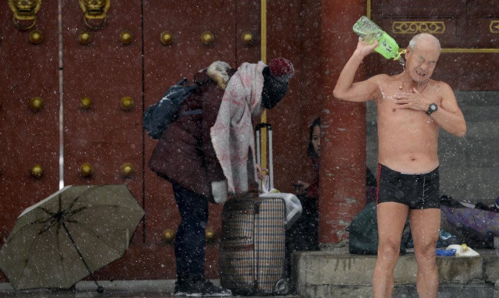 Un nadador chino vierte agua sobre su cuerpo para limpiarse después de nadar en el lago Shichahai, en medio de las tormentas de nieve que han sacudido China estos días interrumpiendo el tráfico, los vuelos y el retraso de los trenes. REUTERS/China Daily