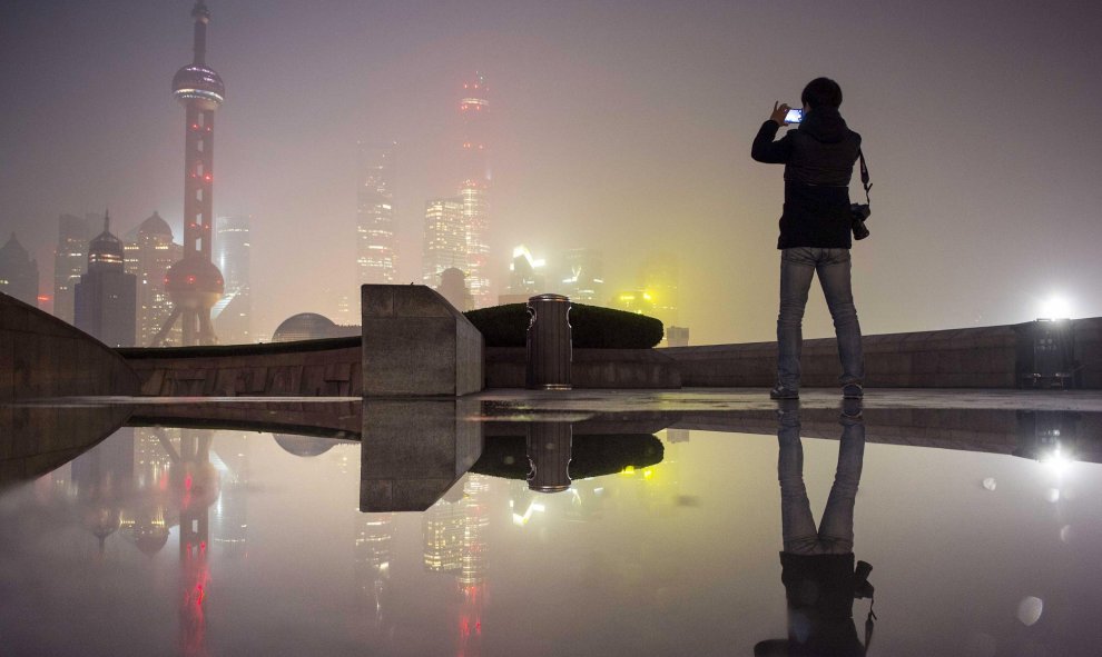 Un hombre saca una foto de la zona financiera del Nuevo Distrito de Pudong que está cubierta por una nube de contaminación. Shangai, China. REUTERS/Stringer