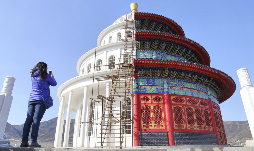 Una mujer fotografía un templo que se divide en dos partes: una parte representa la entrada del templo de Heaven y la otra mitad, un estudio de producciones de cine típicas del occidente. Provincia de Hebei, China. REUTERS/Stringer