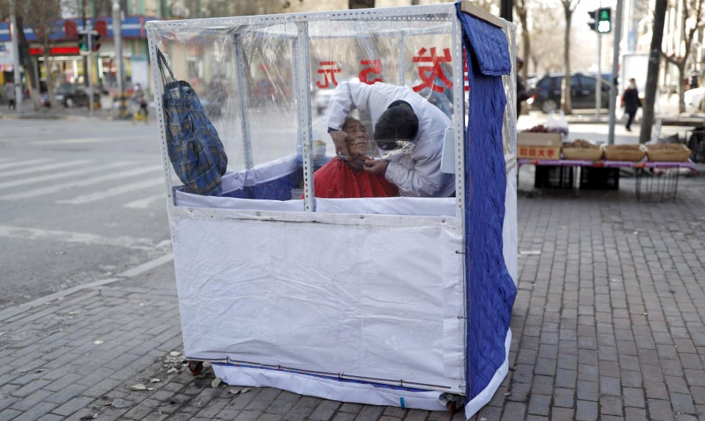 Un barbero afeita a un cliente en una pequeña tienda situada en la acera. Provincia de Liaoning, China. REUTERS/Sheng Li