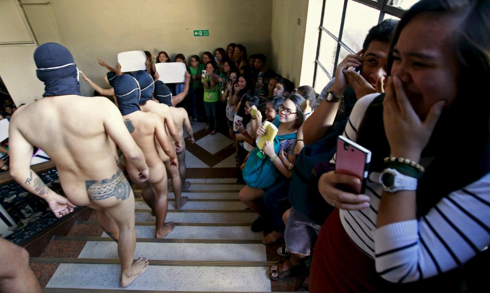 Unos estudiantes filipinos se ruborizan al ver el 'desfile' de Alpha Phi Omega, una fraternidad que camina desnuda durante la Ofrenda del Año en la Universidad de Manila, Filipinas. REUTERS/Romeo Ranoco