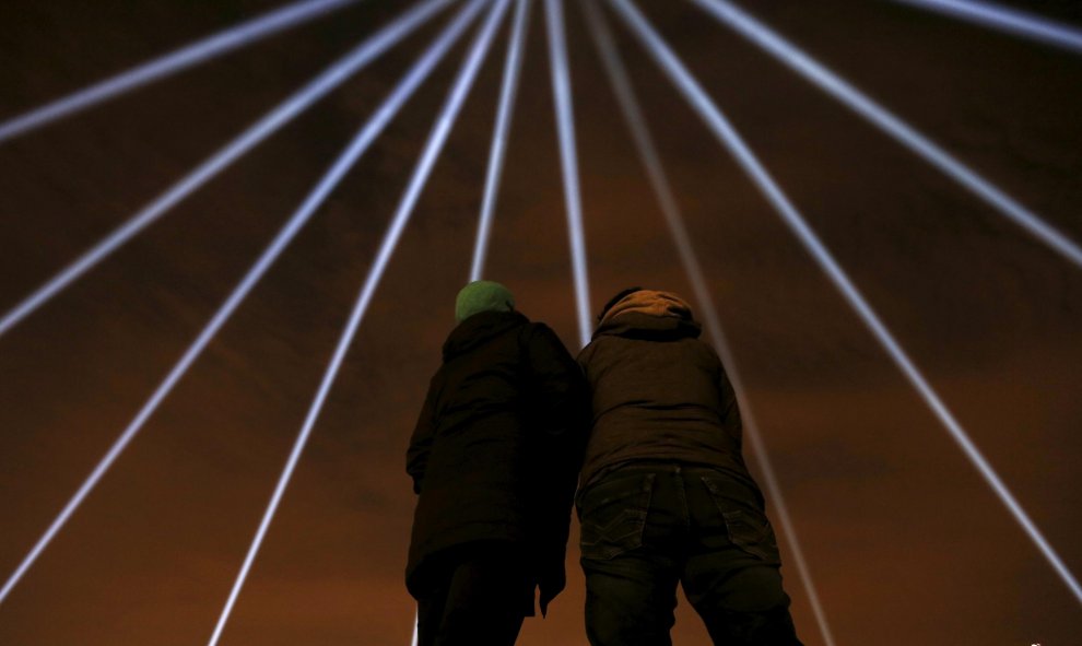 Una pareja observa los rayos de luz azules que son proyectados durante una vigilia para recordar a las víctimas del tiroteo masivo de Quebec, Canadá. REUTERS/Christinne Muschi