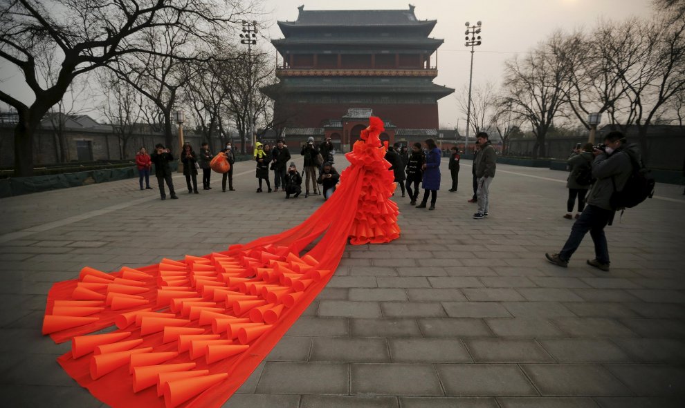 El artista china Kong Ning camina con su traje realizado con cientos de globos naranjas frente a la torre del tambor en una parte histórica de Pekín, China. REUTERS/Damir Sagolj