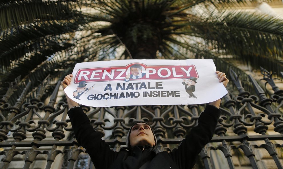 Un hombre sostiene una pancarta que dice "Renzipoly, jugamos juntos en Navidad" en frente del Banco de Italia, durante una protesta en Roma. REUTERS/Alessandro Bianchi