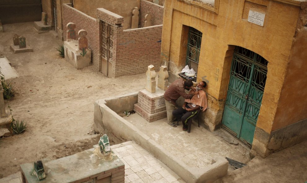 Un barbero afeita a un hombre en la Ciudad de los Muertos de El Cairo. REUTERS/Asmaa Waguih