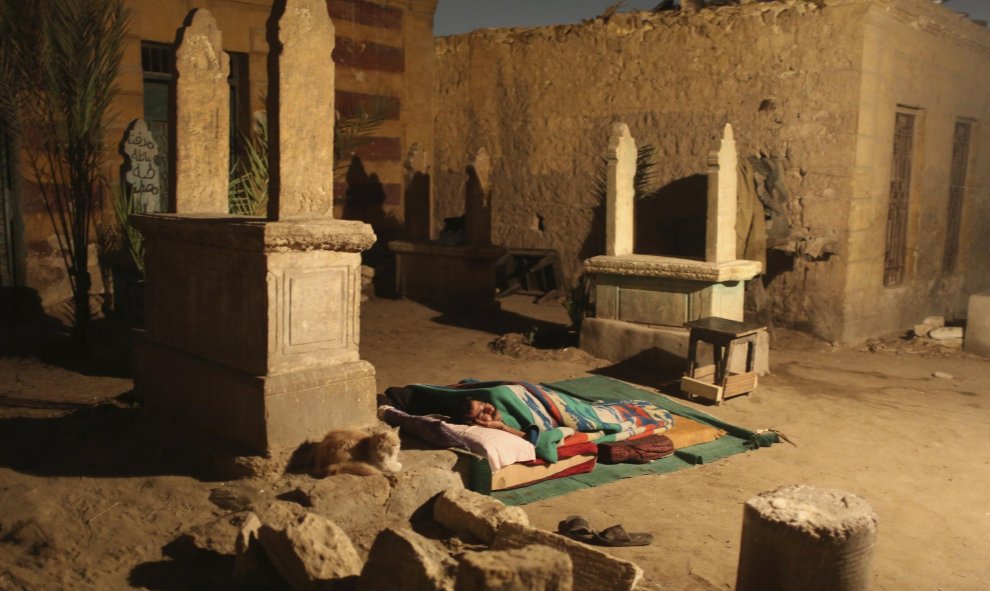 Un hombre duerme entre varias tumbas frente a su vivienda de una sola habitación en la Ciudad de los Muertos, la necrópolis de El Cairo donde habitan desce hace cientos de años docenas de miles de personas. REUTERS/Asmaa Waguih