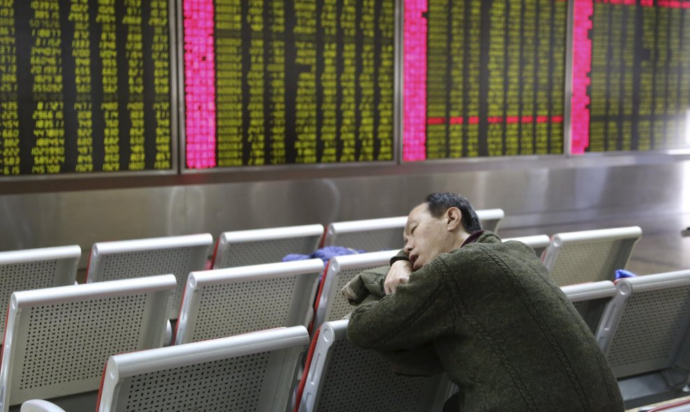Un inversor duerme frente a la pantalla que muestra información sobre las acciones en una oficina de bolsa en Pekín. EFE/How Hwee Young