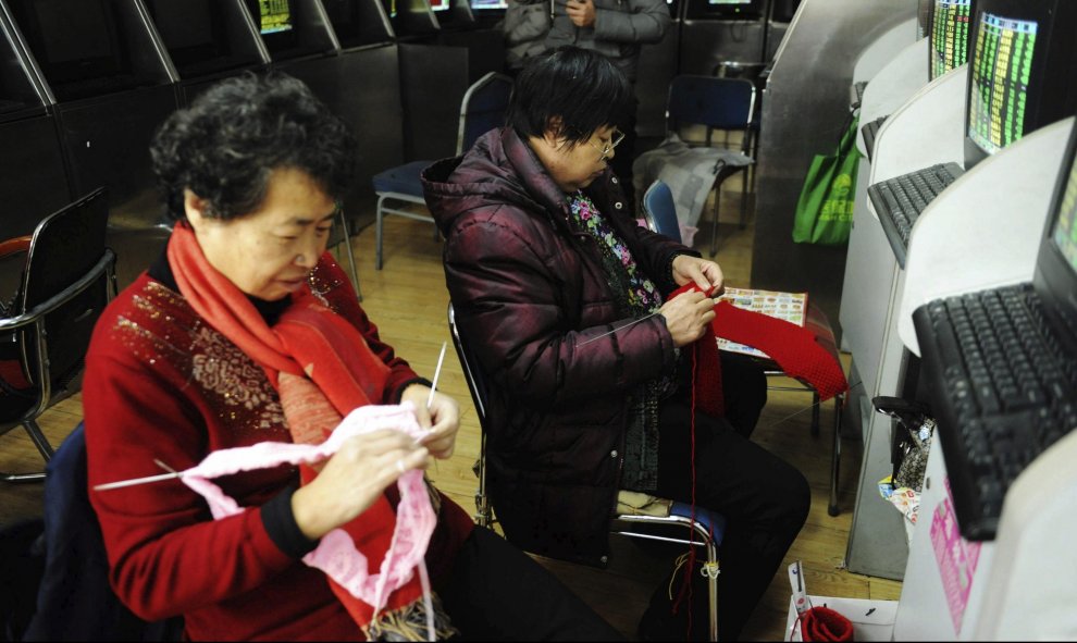 Dos inversoras hacen punto en una agencia de corredores de Qingdao, provincia de Shandong, China. EFE/Yu Fangping