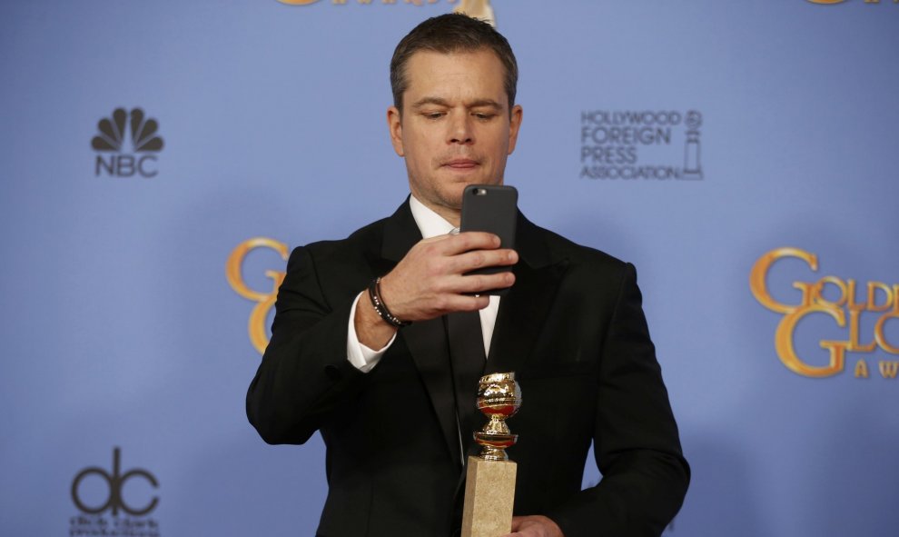 Matt Damon toma una foto mientras posa en la alfombra roja con su premio al mejor actor protagonista (Musical o Comedia) por su papel en "Marte" en la 73ª gala de los Globos de Oro en Beverly Hills, California. REUTERS / Lucy Nicholson