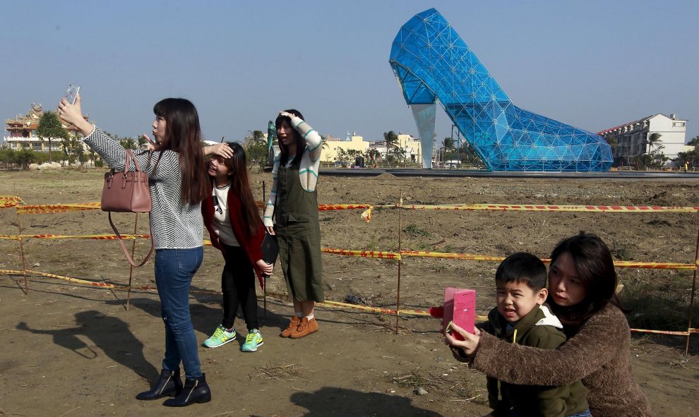 Unos taiwaneses se sacan selfies delante de la nueva iglesia en construcción con forma de zapato. La forma del templo simula el zpato de la Cenicienta para atraer a las mujeres. Chiayi, Taiwán. REUTERS/Pichi Chuang