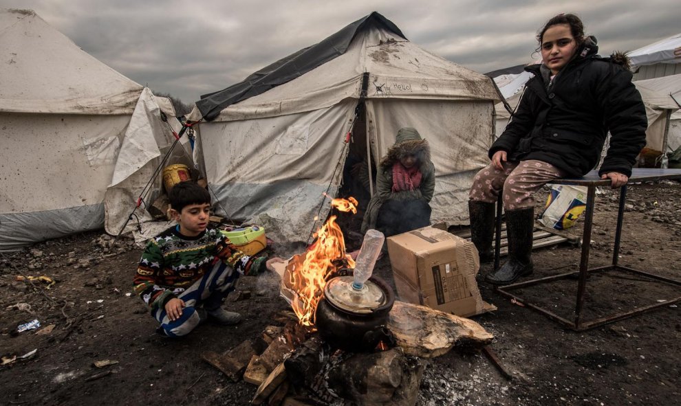 Varios inmigrantes intentan entrar en calor con un brasero en el campamento cerca de Dunkerque, donde viven alrededor de 2.500 de refugiados./AFP