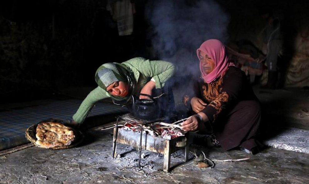Dos mujeres de la familia Hamadeh cocinan en la cueva que les sirve de vivienda, en las afueras del pueblo de Mufagra, cerca de la ciudad cisjordana de Hebrón.  EFE/Abed Al Hashlamoun