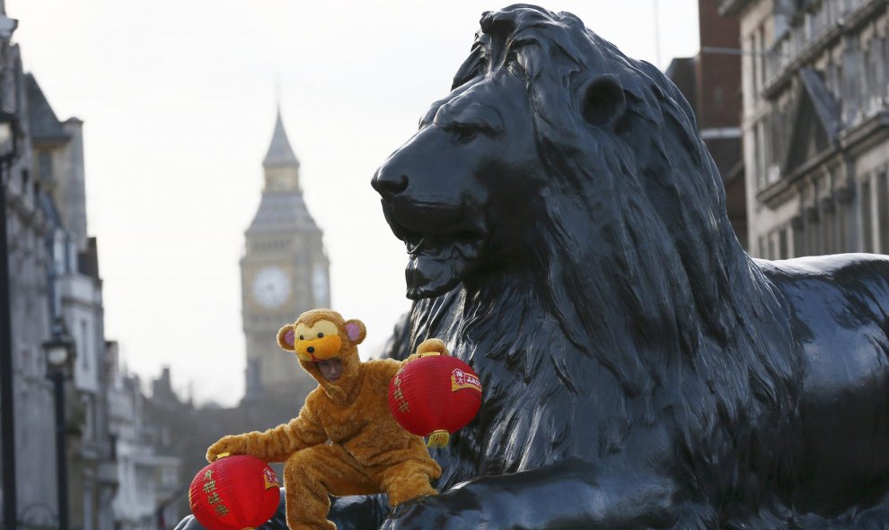 Un hombre disfrazado de mono posa desde uno de los leones de Trafalgar Square para dar la bienvenida al Año Nuevo del Mono de Fuego Chino, en Londres, Inglaterra. REUTERS/Stefan Wermuth