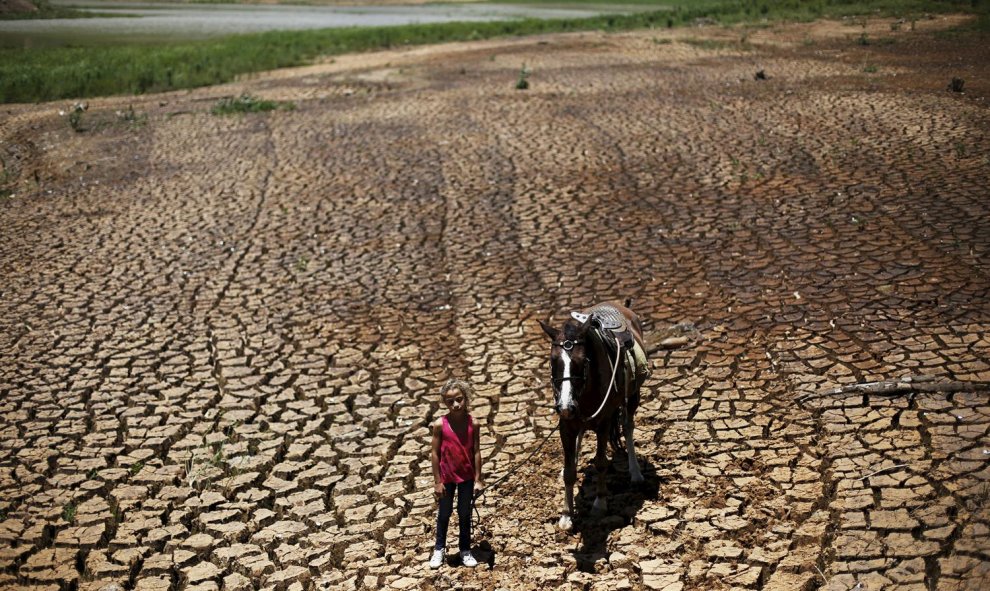 Una niña posa con su caballo en la tierra agrietada por la sequía en la presa Atibainha, en Cantareira, Nazare Paulista, cerca de Sao Paulo, Brasil. REUTERS / Nacho Doce