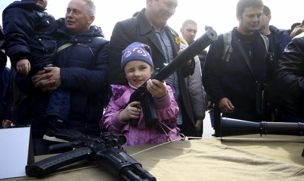 Un pequeña coge un arma para inspeccionarla durante la celebración del Día de Rusia, en Sevastopol, Crimea. REUTERS/Pavel Rebrov