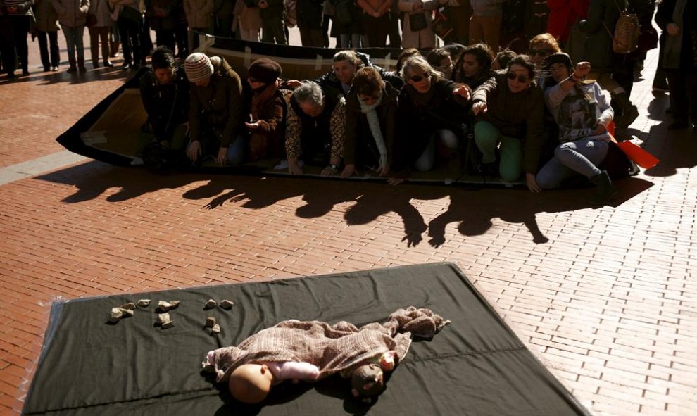 Unas personas simulan el hudimiento de una embarcación con refugiados representando al niño turco Aylan, en la manifestación en Málaga.  REUTERS/Jon Nazca