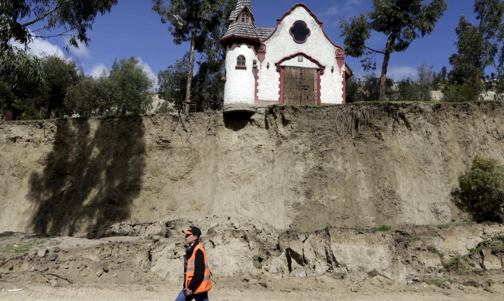 Un trabajador camina en frente de una capilla tras del deslizamiento de tierra producido por las fuertes lluvias en Jupapina, La Paz (Bolivia). REUTERS/David Mercado