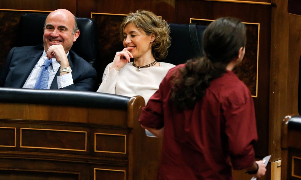 El líder de Podemos, Pablo Iglesias (d), pasa junto a los ministros en funciones de Economía, Luis de Guindos (i), y de Agricultura, Isabel García Tejerina. EFE/Ballesteros
