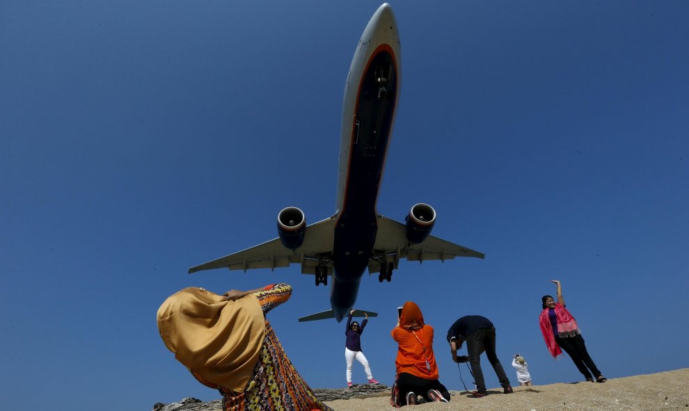 Unos turistas sacan fotos mientras un avión 'se pasea' por la Playa de Mai Khao Beach, en el Aeropuerto Internacional de Phuket, Tailandia. REUTERS/Athit Perawongmetha