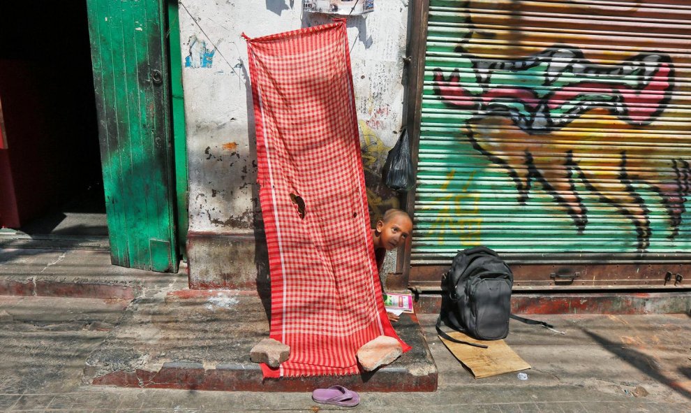 Un niño sin hogar estudia fuera de una tienda cerrada en una calle en Calcuta. REUTERS/Rupak De Chowdhuri