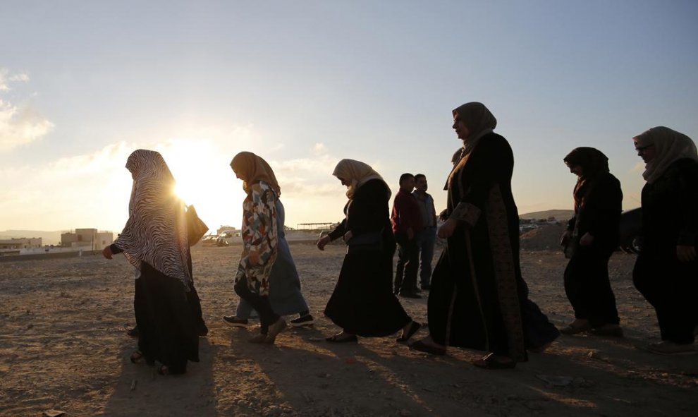 Mujeres palestinas caminan al amanecer hacia el puesto de control de Qalandia, un punto entre la ciudad cisjordana de Ramala y Jerusalén, tras el anuncio del primer ministro israelí, Benjamin Netanyahu, de una serie de medidas de castigo y disuasión contr