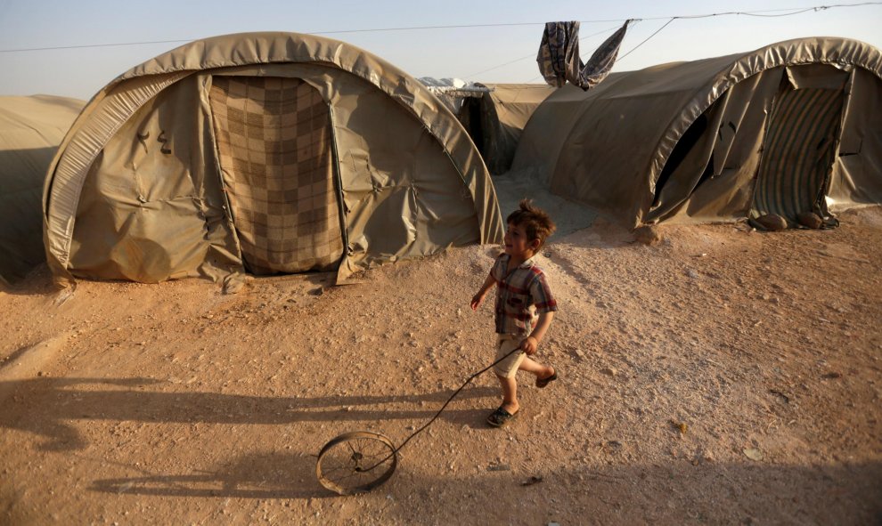 Un niño sirio refugiado juega con una rueda en el campo de Jrzinaz, en la parte sur de Idlib, Siria. REUTERS / Khalil Ashawi