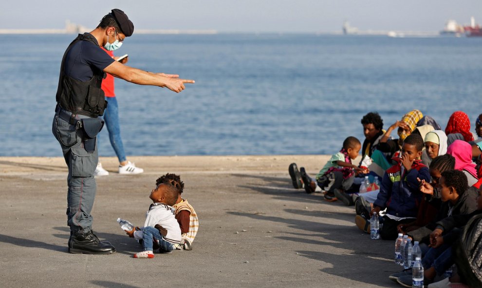 Un policía habla con niños migrantes en el puerto siciliano de Augusta, en Italia. REUTERS/Antonio Parrinello