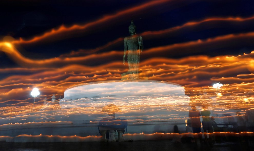 Unos monjes budistas rodean con sus velas una estatuda de un buda durante el día de Asanha Puja, la nochel del budista Lent en Bangkok, Thailandia. REUTERS/Chaiwat Subprasom