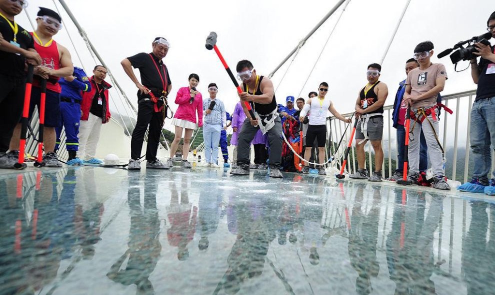 Un visitante golpea el suelo de cristal del puente con un martillo en una prueba de seguridad. Visual China Group