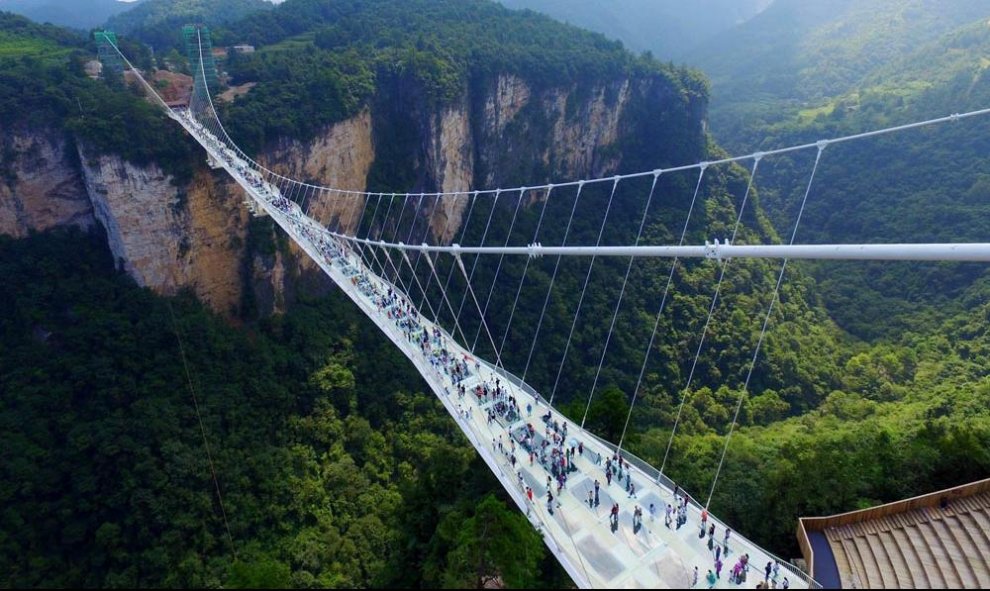 Los turistas caminan por el puente colgante con el suelo de cristal, en el parque natural de Zhangjiajie, en la provincia china de Hunan. EFE / EPA / Shao Ying