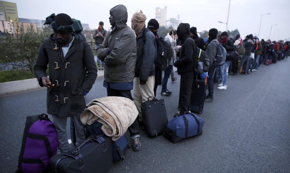 Refugiados hacen cola para ser evacuados de la 'Jungla' de Calais. REUTERS/Neil Hall