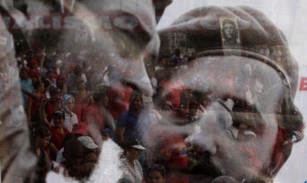 Varias personas observan un poster con la imagen de Fidel Castro y Che Guevara durante la celebración del Primero de Mayo en la Habana en 2013./REUTERS/Desmond Boylan/File Photo