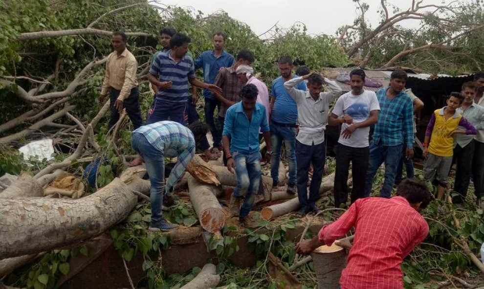 Gente retirando los troncos de los árboles de una carretera después de los fuertes vientos y tormentas en Alwar, en el estado occidental de Rajasthan, India. REUTERS