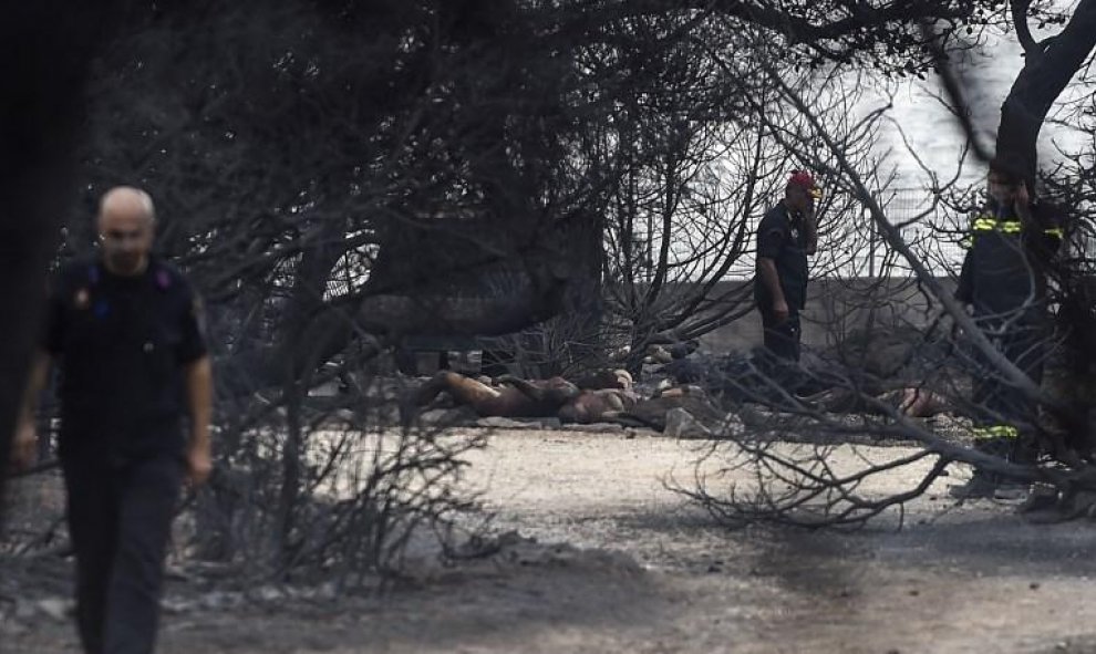 Rescatadores junto a las víctimas del incendio de Mati, cerca de Atenas - AFP