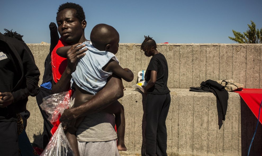 Una mujer subsahariana sostiene a su hijo antes de ser trasladados a otra parte del puerto de Algeciras. Cerca e 400 migrantes han pasado varias días enteros en los barcos de rescate o en el suelo por falta de espacio en otros lugares. JAIRO VARGAS