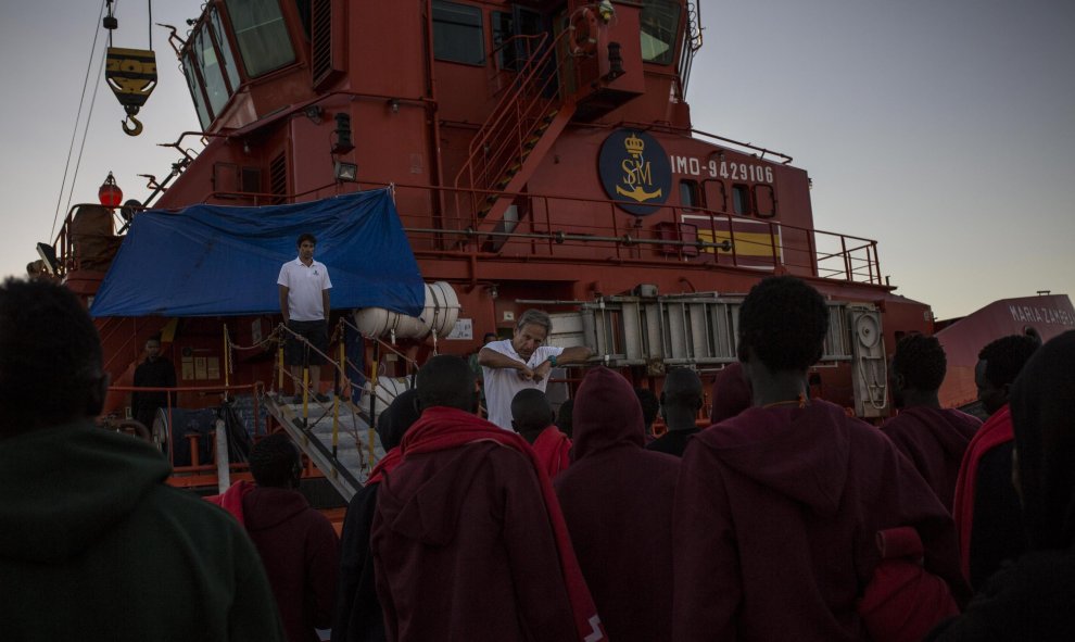 El capitán de la Guardamar María Zambrano, Ángel Téllez, habla con los migrantes atrapados en el puerto de Algeciras antes de que suban al barco en el que pasarán la noche por falta de espacio en otras estancias. JAIRO VARGAS